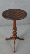 A tripod table with a circular inlaid chessboard tilt top, on a turned stem with tripod legs. H.70