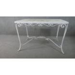 A white painted wrought iron garden table, of rectangular form with scrolling detail, the