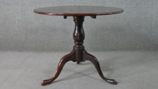 A 19th century mahogany tilt top table, with a circular top on a turned baluster stem, on a tripod