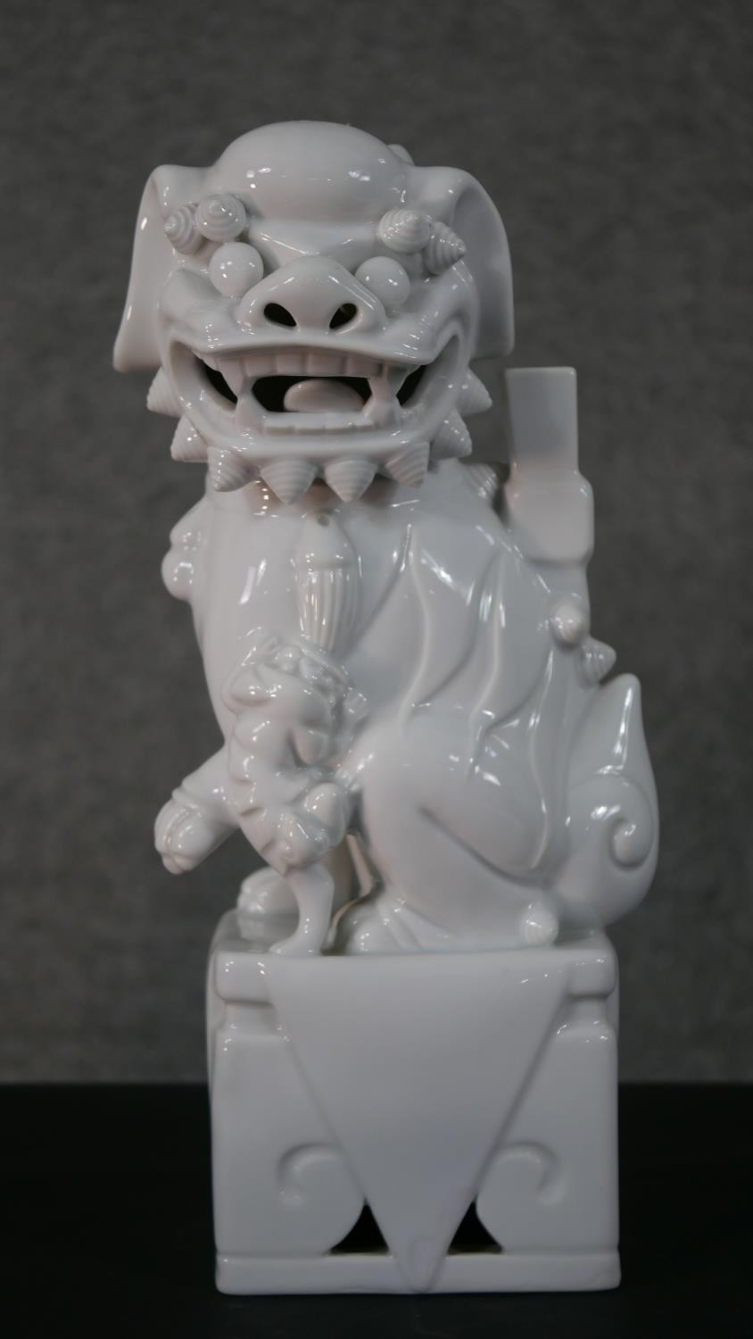 A 20th century blanc de chine Chinese ceramic foo dog on pierced square base. H.35 W.12 D.10cm