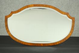 A walnut framed mirror of elongated shield shape, with a bevelled plate. H.44 W.74cm.
