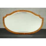 A walnut framed mirror of elongated shield shape, with a bevelled plate. H.44 W.74cm.