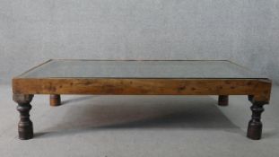 An Indian hardwood coffee table formed from a pair of antique studded doors with an inset plate