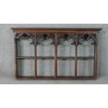 A gothic revival oak wall shelf, with four arched sections, the top of each of trefil form and