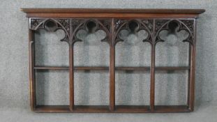 A gothic revival oak wall shelf, with four arched sections, the top of each of trefil form and