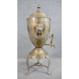 An early 20th century engraved brass samovar on tripod stand with lion head handles and an