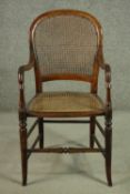 A Victorian fruitwood open armchair, with a caned back and seat, with turned arms and legs, joined