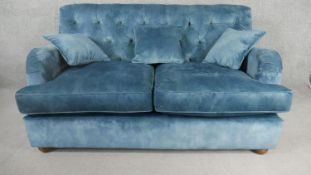 A contemporary Victorian style sofa, upholstered in blue velour, with a buttoned back, on turned bun