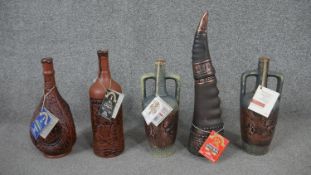 A collection of unopened red wine display bottles, different designs, some with labels.