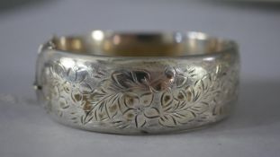 A boxed engraved silver clip cuff bangle and safety chain, decorated with leaves and flowers. 37g