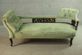 An Edwardian chaise longue, upholstered in green buttoned velour, the back panel carved and