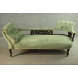 An Edwardian chaise longue, upholstered in green buttoned velour, the back panel carved and