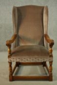 An oak wainscot style wingback armchair, upholstered in brown velour with studded detail, with