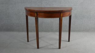 An Edwardian mahogany demi-lune card table, the top inlaid with a shell patera, with a burgundy