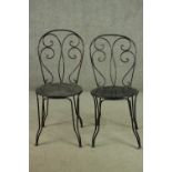 A pair of wrought iron garden chairs, with a circular pierced seat.