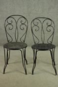 A pair of wrought iron garden chairs, with a circular pierced seat.