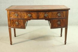 A George III style flame mahogany bowfronted kneehole desk, with a tooled brown leather skiver