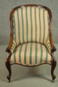 A Victorian rosewood armchair, upholstered in striped fabric, with scrolling arms, on scrolling