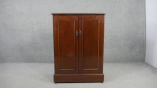 A walnut two door side cabinet, enclosing two shelves, on a plinth base.H.105 W.70 D.43cm