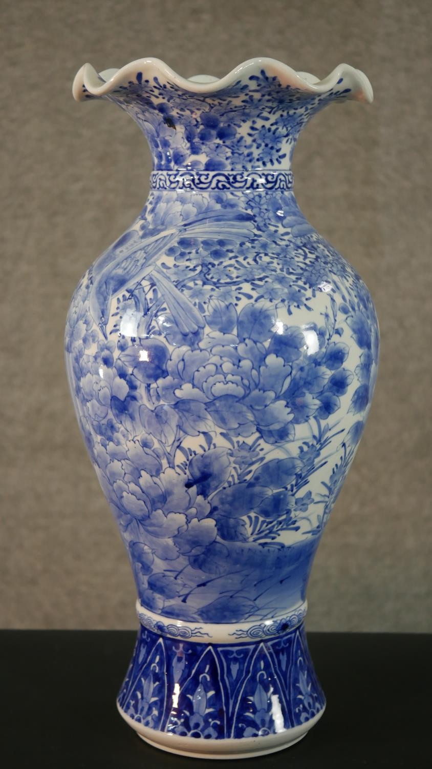 A large Japanese early 20th century blue and white hand painted porcelain vase with fluted edge.