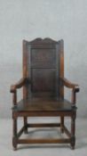 A late 19th century oak wainscot armchair, the panelled back with scrolling top rail, over open