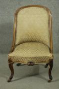 A Victorian walnut nursing chair, upholstered in green fabric, on carved cabriole legs.