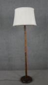 A circa 1920s walnut standard lamp, with a white shade, the stem turned in some places, on a