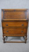 An oak bureau, the fall front opening to reveal pigeonholes, over two long drawers, on cup and cover