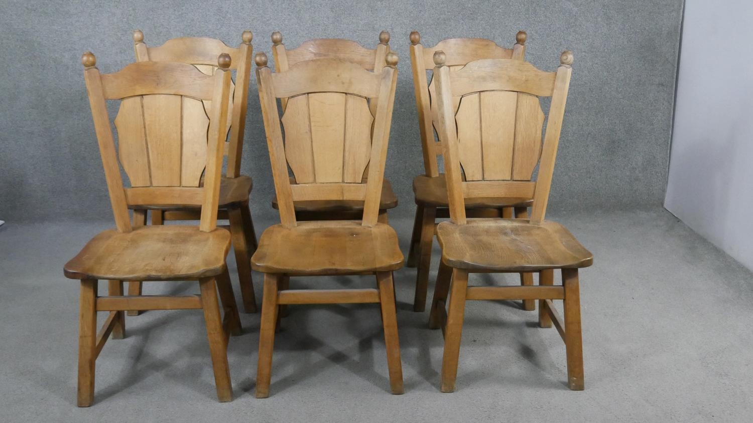 A set of six oak dining chairs, the shaped plank back, over a solid seat, on splayed square