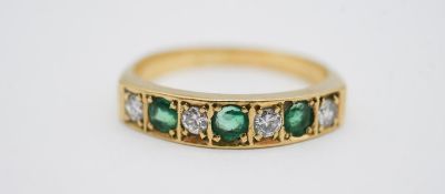 An 18 carat yellow gold emerald and diamond half eternity ring, set with four round brilliant cut