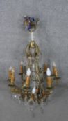 A scrolling gilt brass and crystal eight branch chandelier with hanging crystal drops and foliate