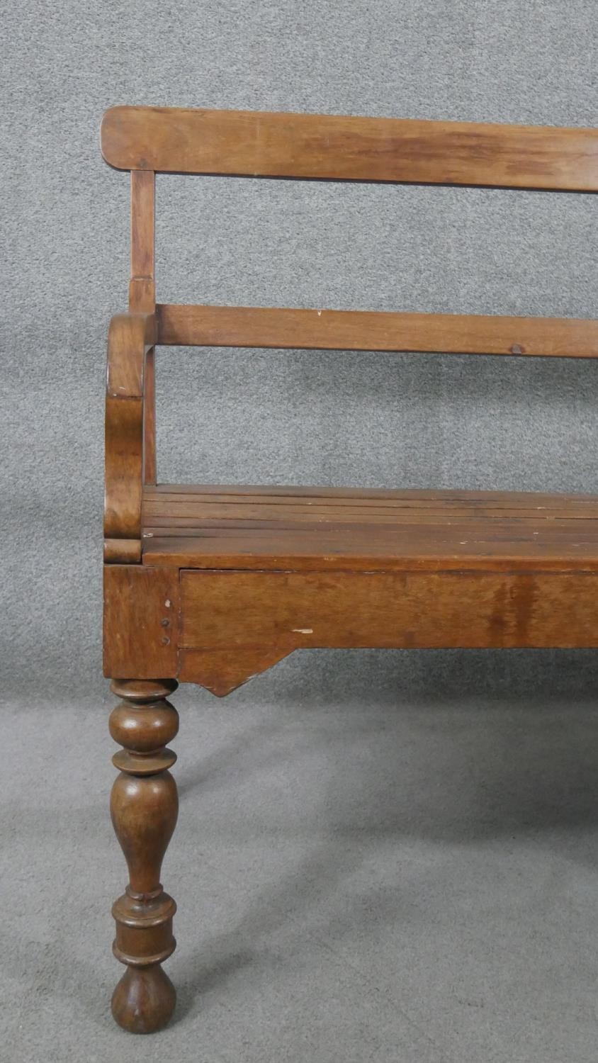 An Indian teak bench, with a bar back and open arms, over a slatted seat, on turned legs. H.93 W.165 - Image 4 of 6