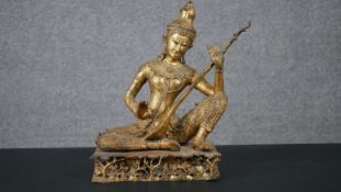 A 19th century gilded bronze Thai figure of Saraswati playing a vina. Animals and trees around the
