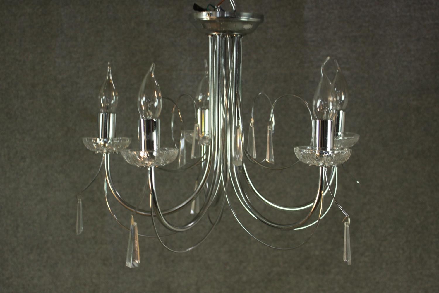 A contemporary chrome chandelier, with five curved branches and glass drip trays. H.37 W.43cm.