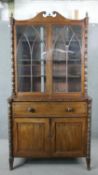 A late Regency mahogany secretaire bookcase, with a swan neck pediment, over arched glazed doors,