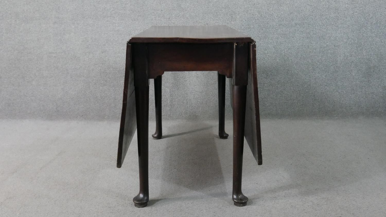 A mid 18th century mahogany drop leaf dining table, with a rectangular top, the legs with pad