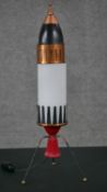 A vintage painted metal rocket ship table lamp on tripod legs. H.49 W.18 D.18cm