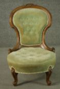 A late 19th century French walnut nursing chair, upholstered with green velour to the buttoned