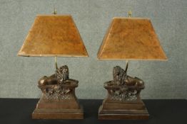 A pair of bronzed effect resin classical style table lamps with lion on pedestal design. H.60 W.