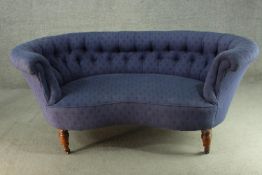 A Victorian walnut sofa, upholstered in blue fabric, with a curved buttoned back and scrolling arms,