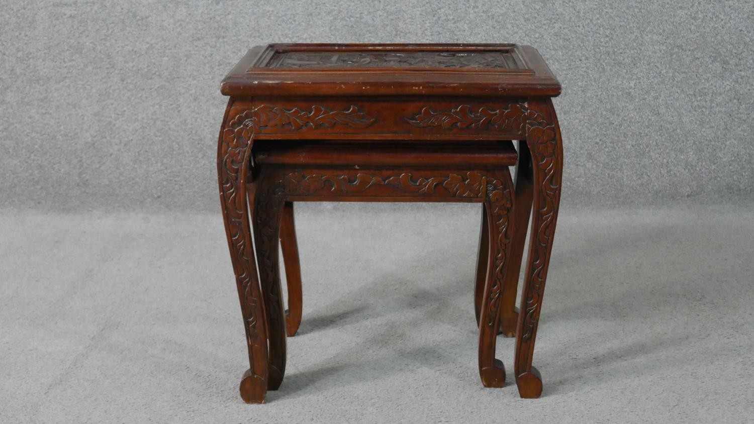 A nest to two Chinese hardwood occasional tables, with carved figural scenes to the top, on