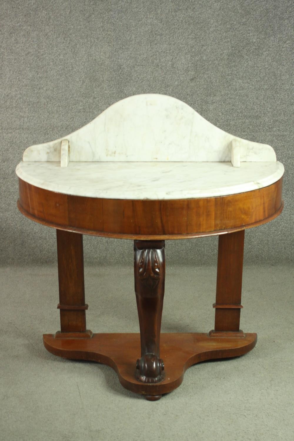 A Victorian walnut demi lune washstand, with a marble back and top, on a carved leg, joined by an