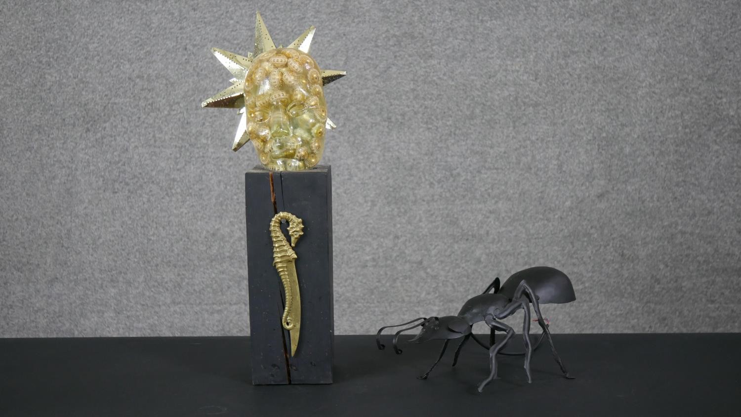 A metal ant wall light along with an acrylic head and star table lamp mounted on a wooden block. H.