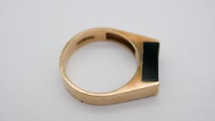 A 9 carat yellow gold and onyx signet style ring, set with a rectangular bezel set onyx to flat