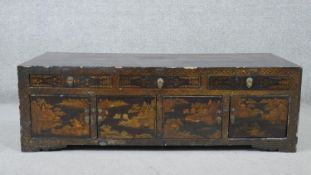 A late Qing Dynasty Chinese black lacquered chest, with a gilt landscape to the top, over three