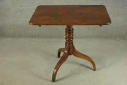 A 19th century mahogany tilt top table, with a rectangular top on a turned stem, on tripod feet. H.