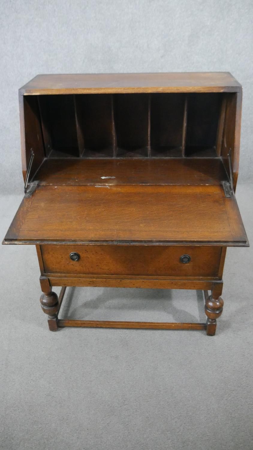 An oak bureau, the fall front opening to reveal pigeonholes, over two long drawers, on cup and cover - Image 3 of 4