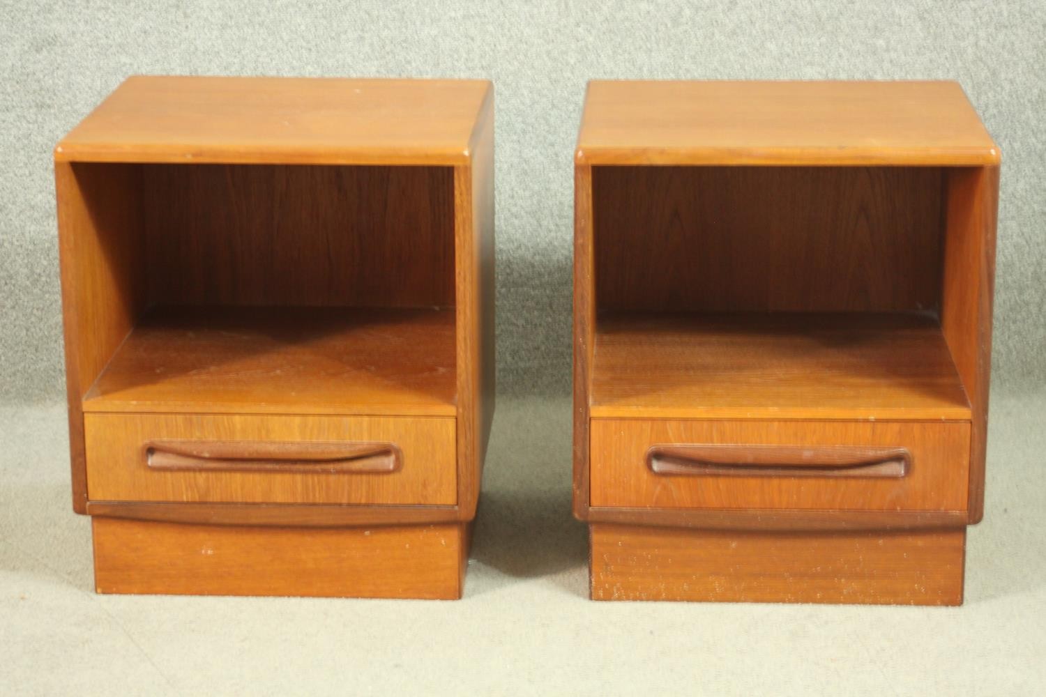 A pair of G-Plan teak bedside cabinets, with a recess over a single drawer, on a plinth base. H.53
