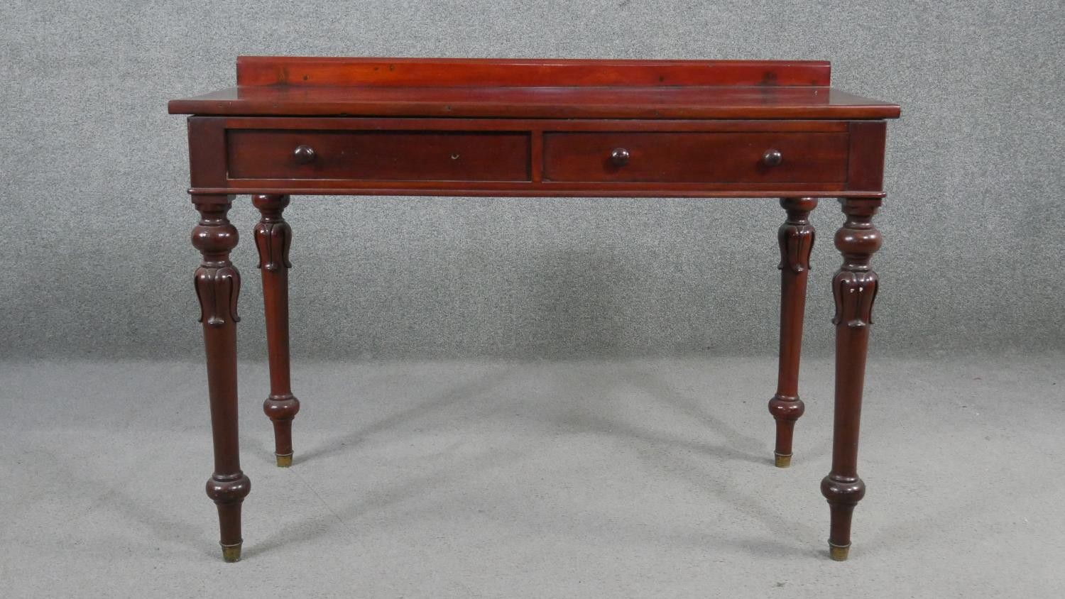 A Victorian mahogany side table, with a gallery back above two short frieze drawers, on carved and
