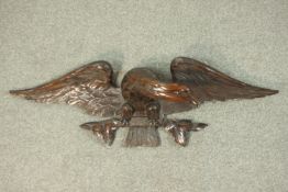 A large early 20th century hand carved mahogany wall mounted eagle with wings, outspread and perched